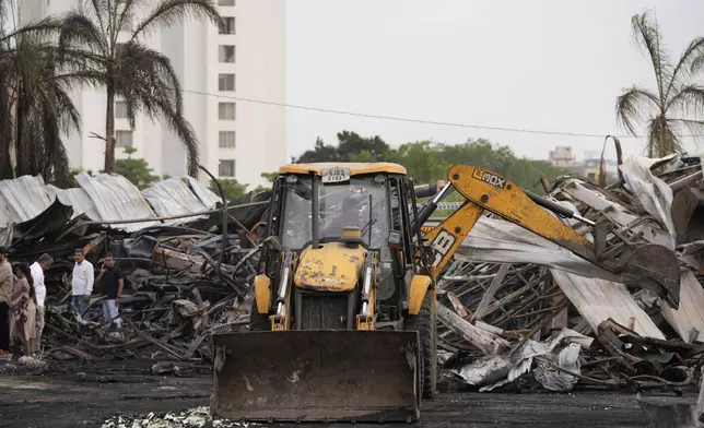 An earthmover removes burnt debris the day after a fire broke out in an amusement park in Rajkot, India, Sunday, May 26, 2024. A massive fire damaged a large part of the park on Saturday, killing more than twenty people and injuring some others, news reports said. (AP Photo/Ajit Solanki)
