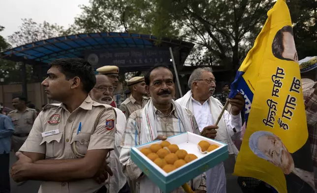 A supporter of the Aam Aadmi Party distributes sweets as he waits with others for the release of the party leader Arvind Kejriwal from Tihar Jail in New Delhi, India, Friday, May 10, 2024. The Supreme Court ordered Arvind Kejriwal's temporary release enabling him to campaign in the country's national election until the voting ends on June 1. (AP Photo /Altaf Qadri)