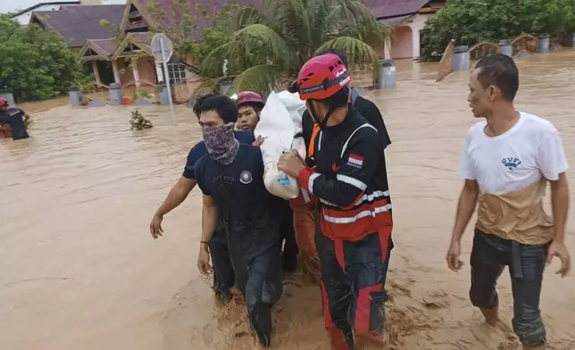 In this Friday, May 3, 2024, photo released by the Wajo Regional Disaster Management Agency (BPBD Wajo), rescuers carry a victim of a flood in Wajo, South Sulawesi, Indonesia. A flood and a landslide hit Indonesia's Sulawesi island, killing a number of people, officials said Saturday. (BPBD Wajo via AP)