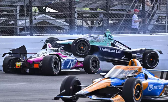 Marcus Ericsson (28), of Sweden, goes over the top of Tom Blomqvist, of England, as the collide in the first turn during the Indianapolis 500 auto race at Indianapolis Motor Speedway in Indianapolis, Sunday, May 26, 2024. (AP Photo/Marty Seppala)