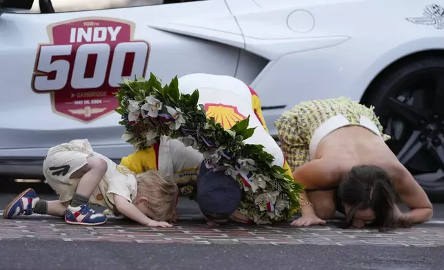 Josef Newgarden, center, kisses the bricks with his son, Kota, left, and wife, Ashley Welch, after winning the Indianapolis 500 auto race at Indianapolis Motor Speedway, Sunday, May 26, 2024, in Indianapolis. (AP Photo/Darron Cummings)