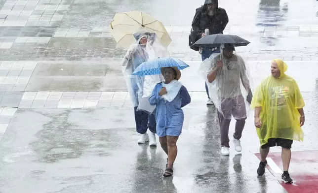 Fans walk in the rain during a thunderstorm delay before the start of the Indianapolis 500 auto race at Indianapolis Motor Speedway in Indianapolis, Sunday, May 26, 2024. (AP Photo/AJ Mast)