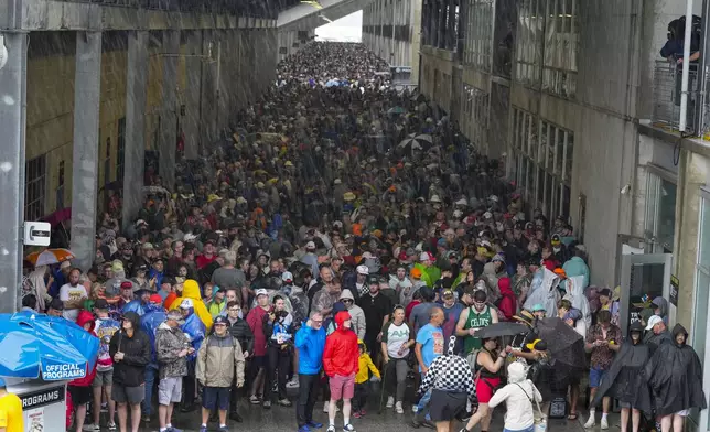 Fans gather under the grandstands as heavy rain and lighting delayed the start of the Indianapolis 500 auto race at Indianapolis Motor Speedway in Indianapolis, Sunday, May 26, 2024. (AP Photo/Michael Conroy)