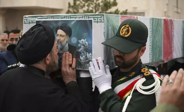 In this photo released by the Iranian Presidency Office, a cleric kisses the flag-draped coffin of President Ebrahim Raisi during a funeral ceremony for him and his companions who were killed in a helicopter crash on Sunday in a mountainous region of the country's northwest, in the city of Tabriz, Iran, Tuesday, May 21, 2024. (Iranian Presidency Office via AP)