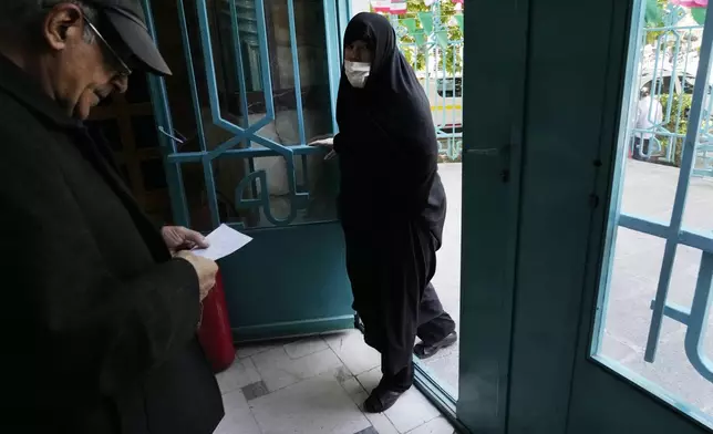 An Iranian woman arrives as a man leaves a polling station during the parliamentary runoff elections in Tehran, Iran, Friday, May 10, 2024. Iranians voted Friday in a runoff election for the remaining seats in the country's parliament after hard-line politicians dominated March balloting. (AP Photo/Vahid Salemi)