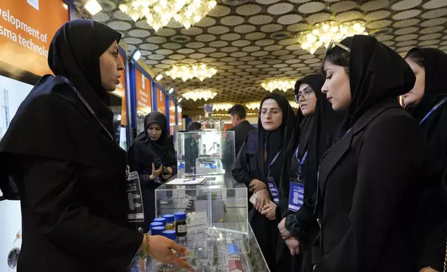 An Iran's Atomic Energy Organization expert speaks with participants of "International Conference on Nuclear Science and Technology" as they visit an exhibition of Iran's nuclear achievements in the central city of Isfahan, Iran, Monday, May 6, 2024. (AP Photo/Vahid Salemi)