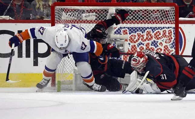New York Islanders' Anders Lee (27) collides with Carolina Hurricanes' Brady Skjei (76) and goaltender Frederik Andersen (31) during the second period in Game 5 of an NHL hockey Stanley Cup first-round playoff series in Raleigh, N.C., Tuesday, April 30, 2024. (AP Photo/Karl B DeBlaker)