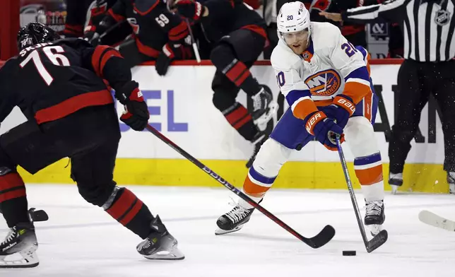 New York Islanders' Hudson Fasching (20) tries to moves the puck around Carolina Hurricanes' Brady Skjei (76) during the first period in Game 5 of an NHL hockey Stanley Cup first-round playoff series in Raleigh, N.C., Tuesday, April 30, 2024. (AP Photo/Karl B DeBlaker)