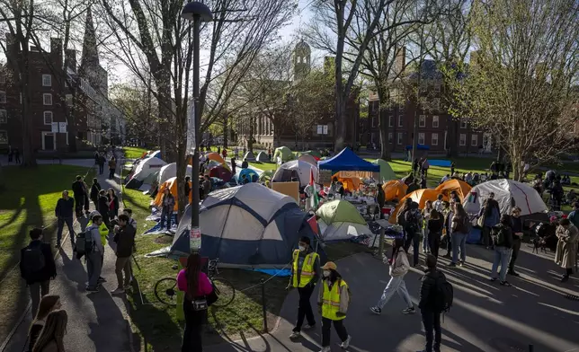 FILE - Students protesting against the war in Gaza, and passersby walking through Harvard Yard, are seen at an encampment at Harvard University in Cambridge, Mass., on April 25, 2024. Participants at the Harvard encampment protesting the war between Israel and Hamas announced they were voluntarily ending their occupation of Harvard Yard. The student protest group said in a statement that the encampment “outlasted its utility with respect to our demands,” and interim Harvard University President Alan Garber agreed to pursue a meeting between those involved in the protest and university officials. (AP Photo/Ben Curtis, File)