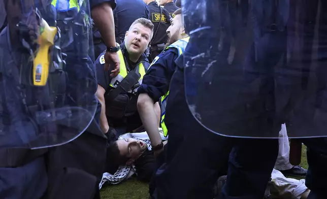 Police detain a demonstrator protesting the war in Gaza as they work to remove a non-sanctioned encampment on the campus of UW-Madison in Madison, Wis., on Wednesday, May 1, 2024. (John Hart/Wisconsin State Journal via AP)