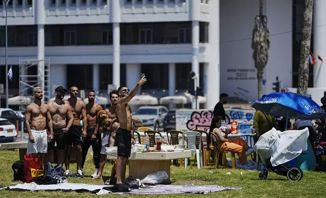 People pose for a selfie in a park during Israel's Independence Day celebrations in Tel Aviv, Tuesday, May 14, 2024. Israelis are marking 76 years since Israel's creation. (AP Photo/Ohad Zwigenberg).