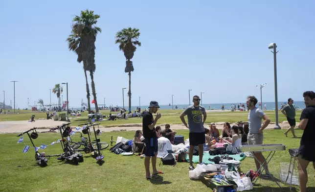 People stand next to a grill as they spend the day on a park during Israel's Independence Day celebrations in Tel Aviv, Tuesday, May 14, 2024. Israelis are marking 76 years since Israel's creation. (AP Photo/Ohad Zwigenberg).