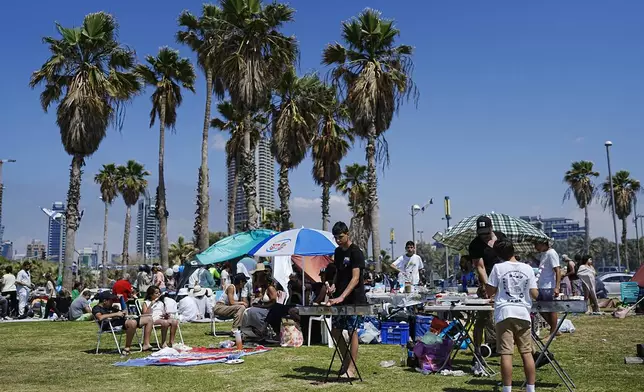 People prepare their food on a grill as they spend the day on a park during Israel's Independence Day celebrations in Tel Aviv, Tuesday, May 14, 2024. Israelis are marking 76 years since Israel's creation. (AP Photo/Ohad Zwigenberg).