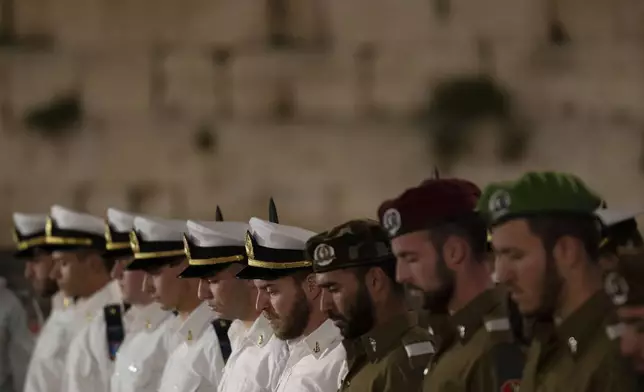 Members of Israeli forces stand in formation to observe a minute of silence as air raid sirens sound to mark Israel's annual Memorial Day for fallen soldiers and victims of nationalistic attacks at the Western Wall, the holiest site where Jews can pray, in the Old City of Jerusalem, Sunday, May 12, 2024. (AP Photo/Leo Correa)