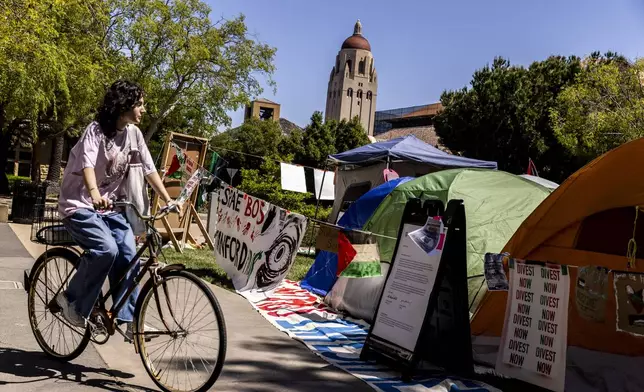 A bicyclist cycles past a tent encampment in White Plaza in support of Palestinians, at Stanford University, in Stanford, Calif., Tuesday, April 30, 2024. (Stephen Lam/San Francisco Chronicle via AP)