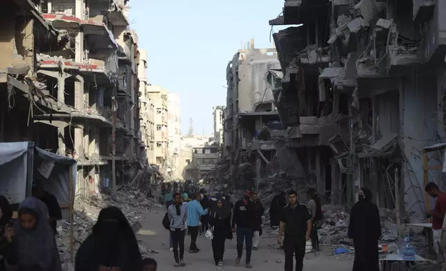 Palestinians walk through the debris after an Israeli air and ground offensive in Khan Younis, southern Gaza Strip, Wednesday, May 15, 2024. (AP Photo/Saher Alghorra)