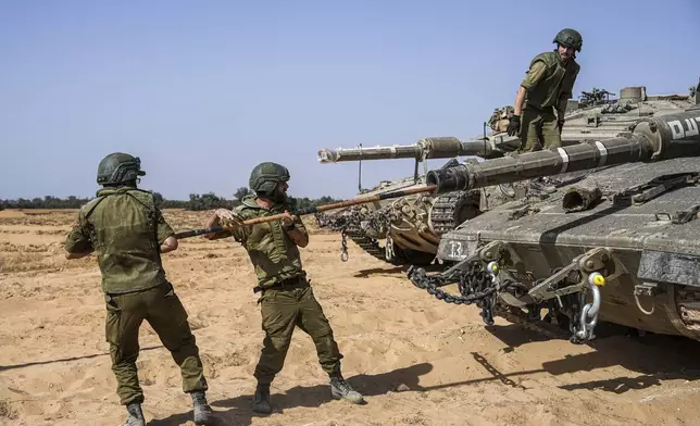 Israeli soldiers work on a tank at a staging ground near the border with the Gaza Strip, in southern Israel, Sunday, May 5, 2024. (AP Photo/Tsafrir Abayov)