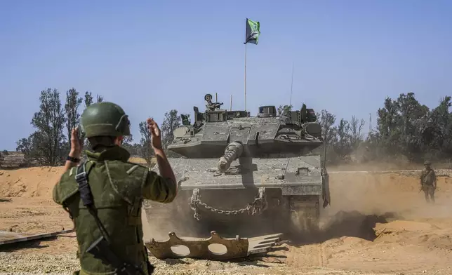 Israeli soldiers directs a tank at a staging ground near the border with the Gaza Strip, in southern Israel, Sunday, May 5, 2024. (AP Photo/Tsafrir Abayov)