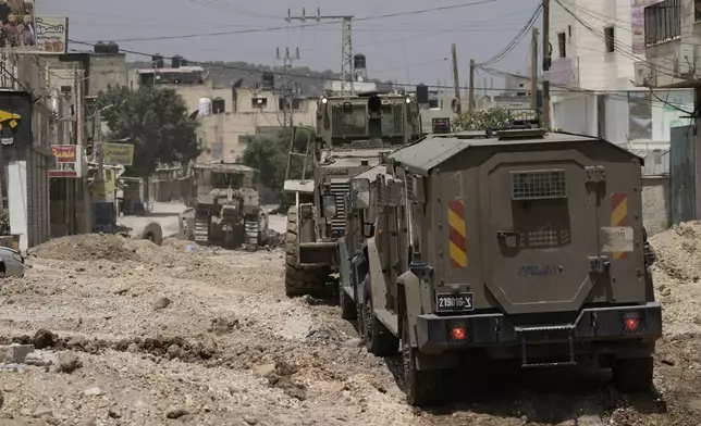 Israeli military vehicles are seen during a raid in the West Bank Jenin refugee camp, Tuesday, May 21, 2024. Israeli forces raided a militant stronghold Tuesday in the occupied West Bank, killing at least seven and wounding several, according to the Palestinian Health Ministry. The raid into the Jenin refugee camp is part of months of surging violence in the Palestinian territory. (AP Photo/Majdi Mohammed)