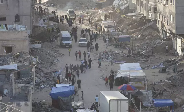 Palestinians walk through the debris after an Israeli air and ground offensive in Khan Younis, southern Gaza Strip, Wednesday, May 15, 2024. (AP Photo/Saher Alghorra)