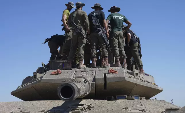 Israeli soldiers work on armored military vehicles at a staging ground near the Israeli-Gaza border, in southern Israel, Wednesday, May 8, 2024. (AP Photo/Tsafrir Abayov)