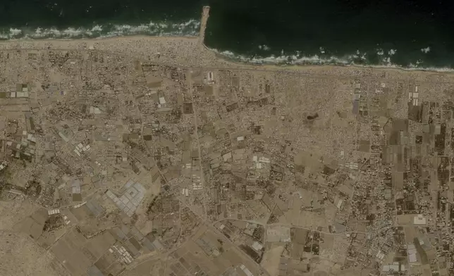 This image provided by Planet Labs PBC shows tent camps line the beach and fill empty lots outside the central Gaza city of Deir al-Balah, Friday, May 24, 2024, housing Palestinians who fled Israel's offensive in Rafah the past three weeks. (Planet Labs PBC via AP)