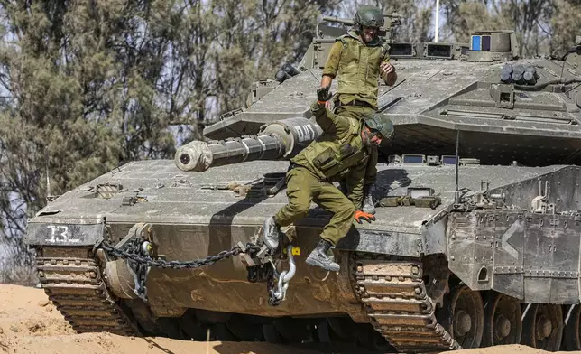 Israeli soldiers jump off a tank at a staging ground near the border with the Gaza Strip, in southern Israel, Sunday, May 5, 2024. (AP Photo/Tsafrir Abayov)