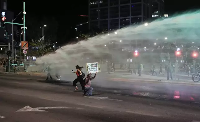 Police use water cannon to disperse demonstrators blocking a road during a protest against Israeli Prime Minister Benjamin Netanyahu's government, and calling for the release of hostages held in the Gaza Strip by the Hamas militant group, in Tel Aviv, Israel, Saturday, May 18, 2024. (AP Photo/Leo Correa)