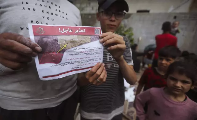 Palestinians hold leaflets dropped by Israeli planes calling on them to evacuate ahead of an Israeli military operation in Rafah, southern Gaza Strip, Monday, May 6, 2024. The order affects tens of thousands of people and could signal a broader invasion of Rafah, which Israel has identified as Hamas' last major stronghold after seven months of war. (AP Photo/Ismael Abu Dayyah)