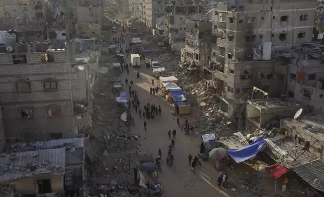 Palestinians walk through the debris after an Israeli air and ground offensive in Khan Younis, southern Gaza Strip, Wednesday, May 15, 2024. (AP Photo/Saher Alghorra)