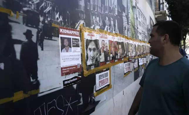 A man looks at a poster of Oryon Hernandez Radoux, 30, second left, who was killed on Oct. 7, 2023, next to posters of hostages held by Hamas in the Gaza Strip, in central Jerusalem, Friday, May 24, 2024. The bodies of Michel Nisenbaum, 59, Hanan Yablonka, 42, and Oryon Hernandez Radoux, three hostages killed on Oct 7, were recovered overnight from Gaza, Israel's army said Friday May 24. (AP Photo/Mahmoud Illean)