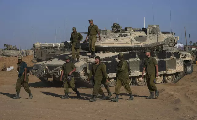 Israeli soldiers walk in a staging area for their tanks near the Gaza border in southern Israel, Friday, May 24, 2024. (AP Photo/Tsafrir Abayov)