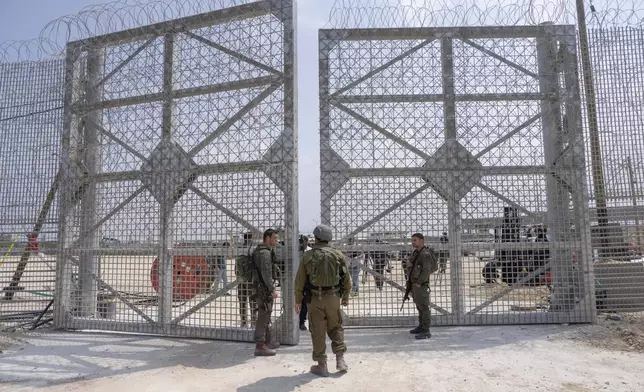 Israeli soldiers gather near a gate to walks through an inspection area for trucks carrying humanitarian aid supplies bound for the Gaza Strip, on the Israeli side of the Erez crossing into Gaza, Wednesday, May 1, 2024. (AP Photo/Ohad Zwigenberg)