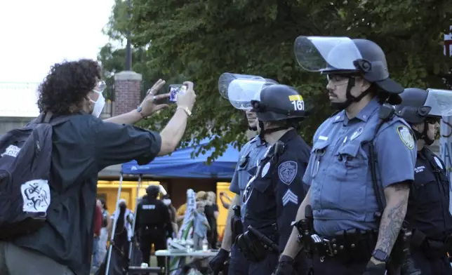 A person uses a mobile device to record members of law enforcement, Tuesday, May 7, 2024, on the University of Massachusetts Amherst campus, in Amherst, Mass. Police moved in Tuesday night to break up an encampment at the school in what appeared in video to be an hours-long operation as dozens of police officers in riot gear systematically tore down tents and took protesters into custody. The protesters established the tent encampment to demonstrate against the war in Gaza. (Kalinka Kornacki via AP)