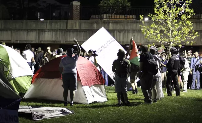 Students and supporters are confronted by members of law enforcement, Tuesday, May 7, 2024, at a tent encampment on the University of Massachusetts Amherst campus, in Amherst, Mass. Police moved in Tuesday night to break up an encampment at the school, in what appeared in video to be a hours-long operation as dozens of police officers in riot gear systematically tore down tents and took protesters into custody. The protesters established the tent encampment to demonstrate against the war in Gaza. (Kalinka Kornacki via AP)
