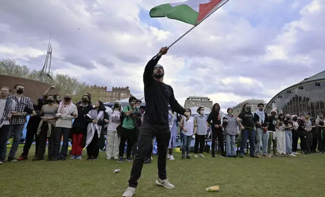 A demonstrator waves a Palestinian flag at a pro-Palestinian encampment at MIT, May 6, 2024, in Cambridge, Mass. Several hundred demonstrators crossed breached barricades to join pro-Palestinian demonstrators that been given a deadline to leave the encampment. (AP Photo/Josh Reynolds)