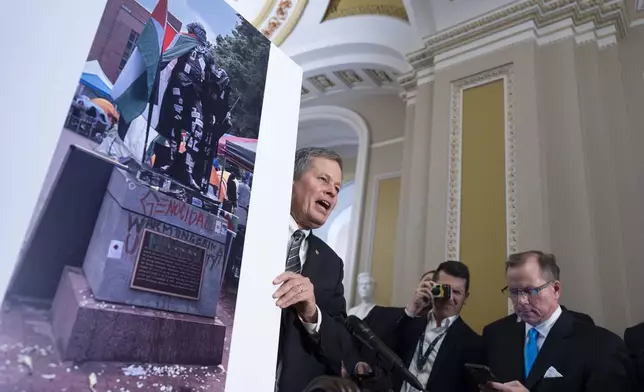 Sen. Steve Daines, R-Mont., holds a photograph of a statue of George Washington defaced with graffiti and covered with a Palestinian flag by protesters at George Washington University, during a news conference at the Capitol in Washington, Wednesday, May 8, 2024. (AP Photo/J. Scott Applewhite)