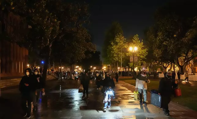 People carry belongings out of an encampment set up by pro-Palestinian demonstrators after police arrived for a raid on the campus at the University of Southern California Sunday, May 5, 2024, in Los Angeles. (AP Photo/Ryan Sun)