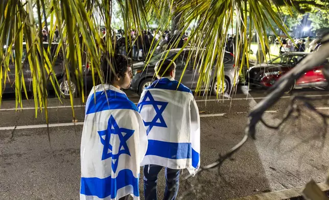 Counter protestors stand draped in Israeli flags across the street from pro-Palestinian demonstrators at Tulane University in New Orleans, Monday night, April 29, 2024. (Chris Granger/The Times-Picayune/The New Orleans Advocate via AP)