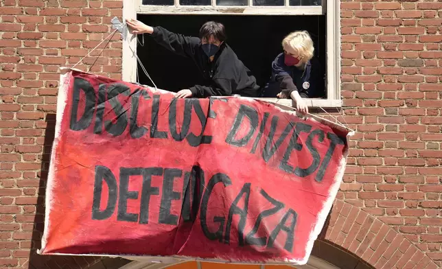 Activists hang a placard from a window of an upper floor of a building at Rhode Island School of Design, Tuesday, May 7, 2024, in Providence, R.I. RISD students and supporters, who have taken over a portion of the building, are demanding that the school condemn Israel's war effort in Gaza, and that the school divest from investments that benefit Israel. (AP Photo/Steven Senne)