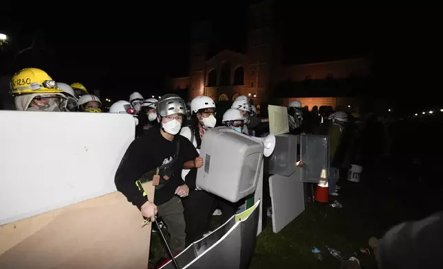 Pro-Palestinian demonstrators use makeshift shields as police advance on them on the UCLA campus Thursday, May 2, 2024, in Los Angeles. (AP Photo/Ryan Sun)