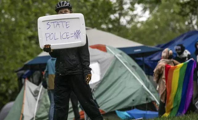 A pro-Palestinian supporter holds a sign reading "State Police=KKK" on the grounds of the University of Virginia, in Charlottesville, Va., where they set up tents, Saturday, May 4, 2024. (Cal Cary/The Daily Progress via AP)