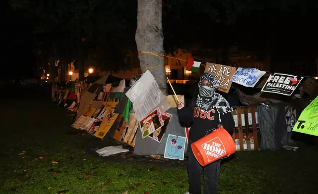 A demonstrator stands in front of an encampment set up by pro-Palestinian demonstrators on the campus at the University of Southern California after police arrived with orders to disperse Sunday, May 5, 2024, in Los Angeles. (AP Photo/Ryan Sun)