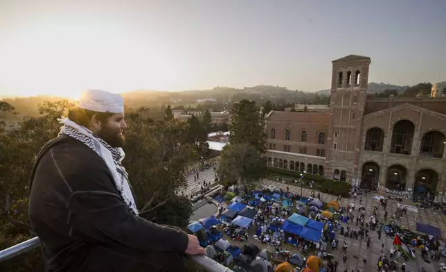 A demonstrator watches an encampment from a construction scaffold on the UCLA campus, after clashes between Pro-Israel and Pro-Palestinian groups, Wednesday, May 1, 2024, in Los Angeles. (AP Photo/Ethan Swope)