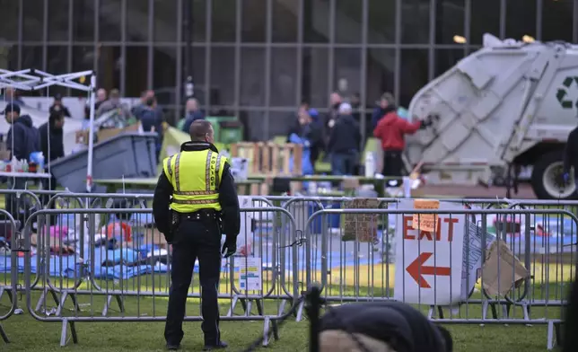 A police officer watches as workers dismantle the remains of a pro-Palestinian encampent at MIT, at dawn on Friday, May 10, 2024, in Cambridge, Mass. (AP Photo/Josh Reynolds)