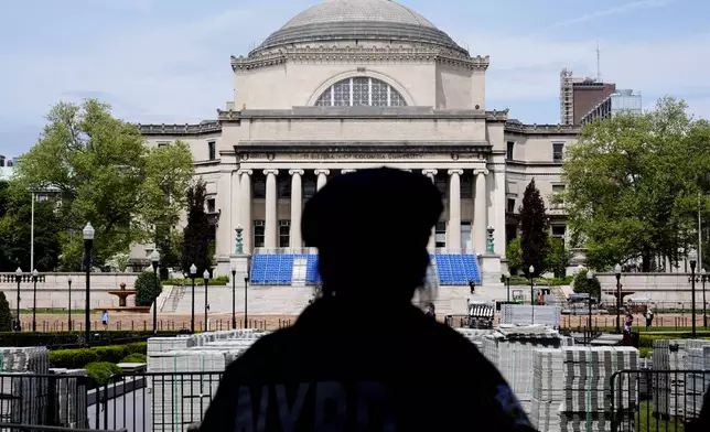 A New York City police officer looks over the center of Columbia University, the usual site of a large graduation ceremony, in New York, Monday, May 6, 2024. The university says it is canceling its university-wide commencement ceremony following weeks of pro-Palestinian protests. Smaller school-based ceremonies are still on for this week and next. (AP Photo/Seth Wenig)