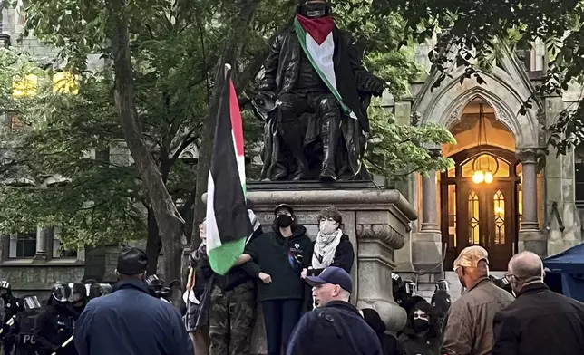Protesters lock arms at the Ben Franklin Statue on Penn campus as police clear the encampment showing support for Palestinians in Gaza, at the University of Pennsylvania, in Philadelphia, Friday, May 10, 2024. (Jessica Griffin/The Philadelphia Inquirer via AP)