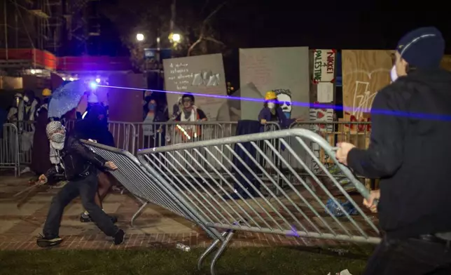 Demonstrators clash at an encampment at UCLA late Tuesday, April 30, 2024, in Los Angeles. Dueling groups of protesters have clashed at the University of California, Los Angeles, grappling in fistfights and shoving, kicking and using sticks to beat one another. (AP Photo/Ethan Swope)