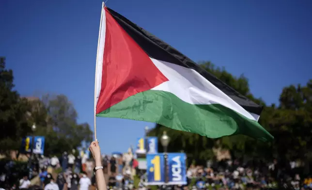 A Palestinian flag is waved as protesters gather on the UCLA campus, after nighttime clashes between Pro-Israel and Pro-Palestinian groups, Wednesday, May 1, 2024, in Los Angeles. (AP Photo/Jae C. Hong)