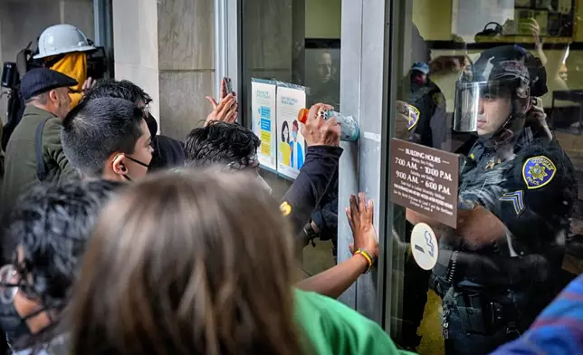 A University police officer blocks a doorway from pro-Palestinian demonstrators entering at Dodd Hall on the UCLA campus on Thursday, May 23, 2024, in Los Angeles. (AP Photo/Ryan Sun)